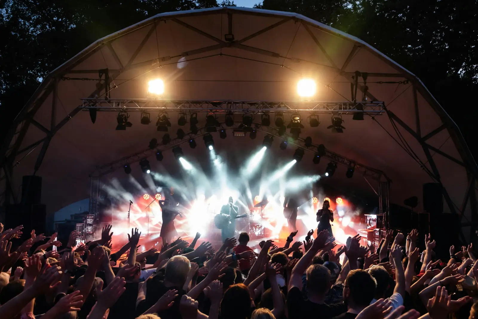 Scène de festival en plein air, mains levées dans la foule